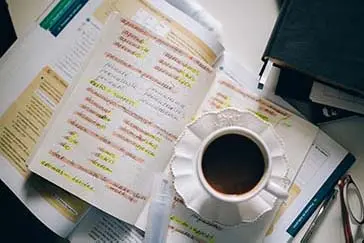 A coffee placed on top of a notebook and a book.