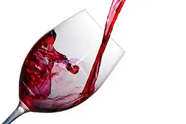 Pouring a red wine on a wine glass.