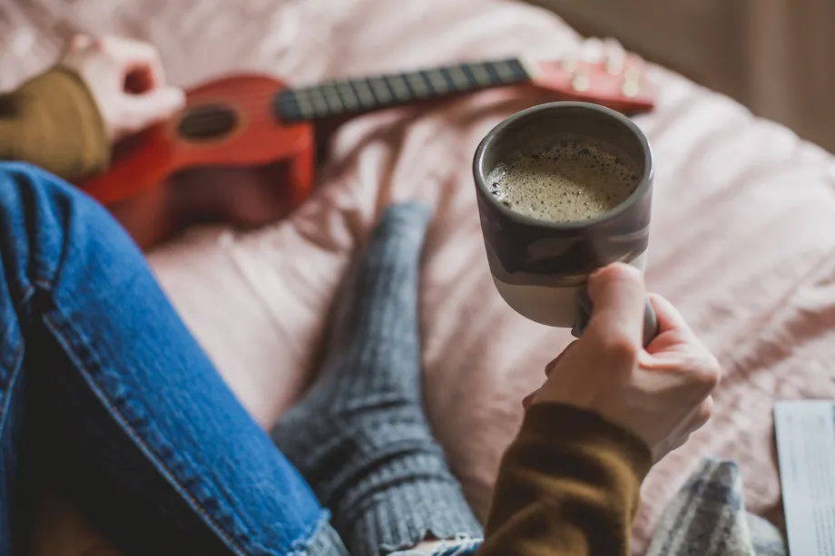 Woman holding coffee in bed